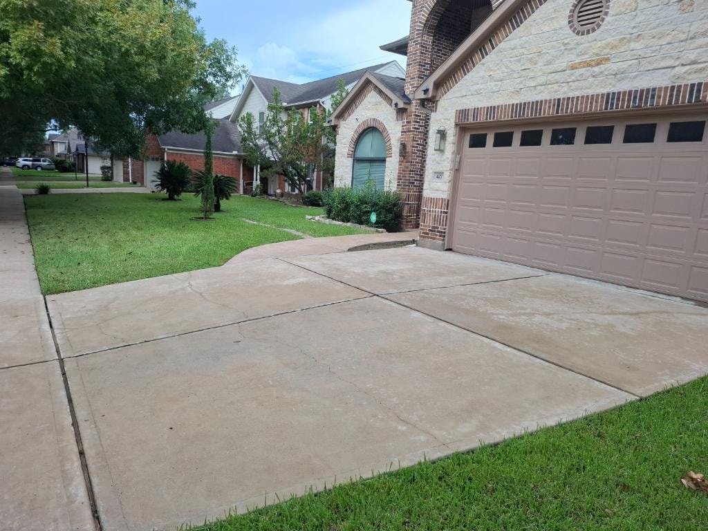 Brick house driveway after pressure washing — clean bright concrete